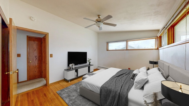 bedroom featuring light wood-style flooring, a baseboard radiator, ceiling fan, and baseboards