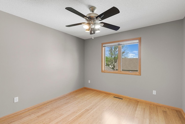 spare room with wood finished floors, ceiling fan, and baseboards