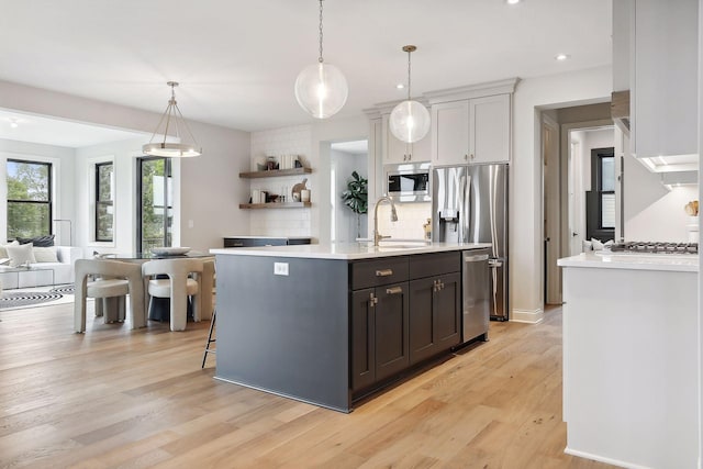 9511 Eagle Ridge Rd, Chanhassen, MN 55317 - kitchen with tasteful backsplash, light countertops, appliances with stainless steel finishes, a kitchen island with sink, and light wood-style flooring