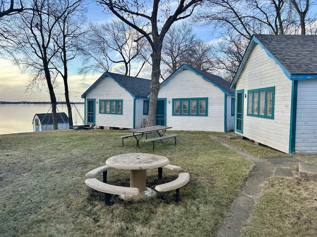 back of house featuring a yard and a shingled roof