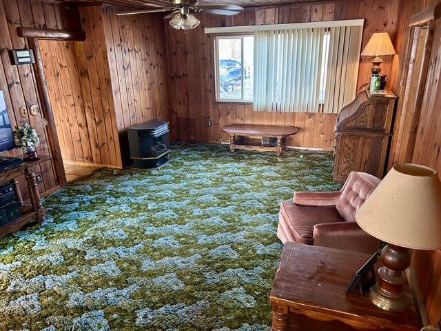 interior space featuring wooden walls, carpet floors, and a wood stove