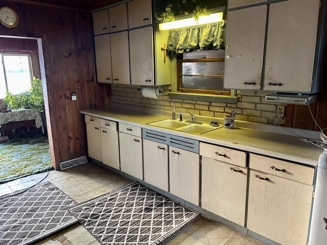 kitchen with light countertops, wooden walls, and a sink
