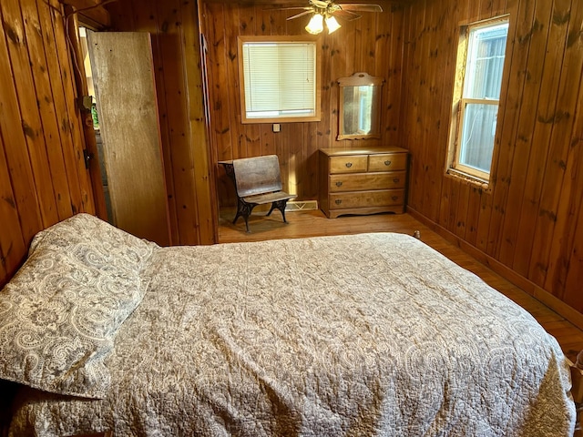 bedroom featuring wood walls, baseboards, and wood finished floors