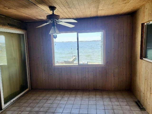 unfurnished room with visible vents, a ceiling fan, wood walls, and wooden ceiling