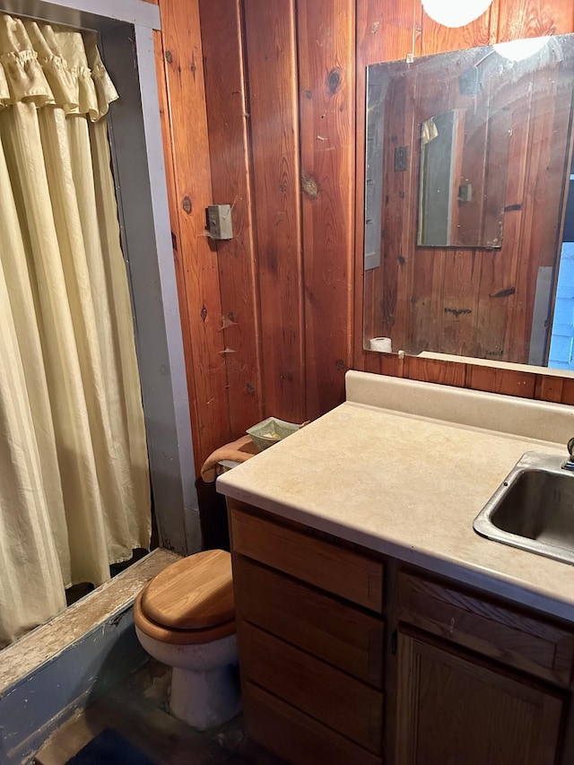 full bathroom with curtained shower, wooden walls, toilet, and vanity