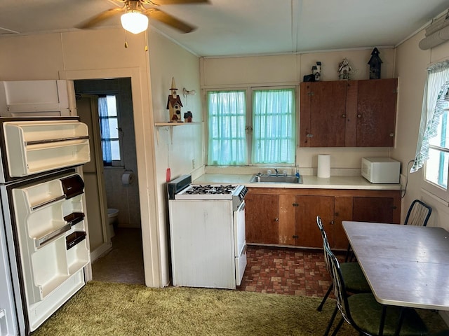 kitchen featuring crown molding, a sink, ceiling fan, white gas range oven, and light countertops