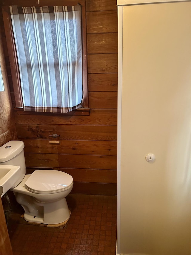 bathroom with toilet and wooden walls