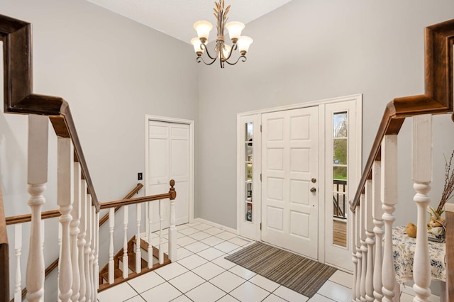 foyer with an inviting chandelier, stairs, a towering ceiling, baseboards, and light tile patterned floors
