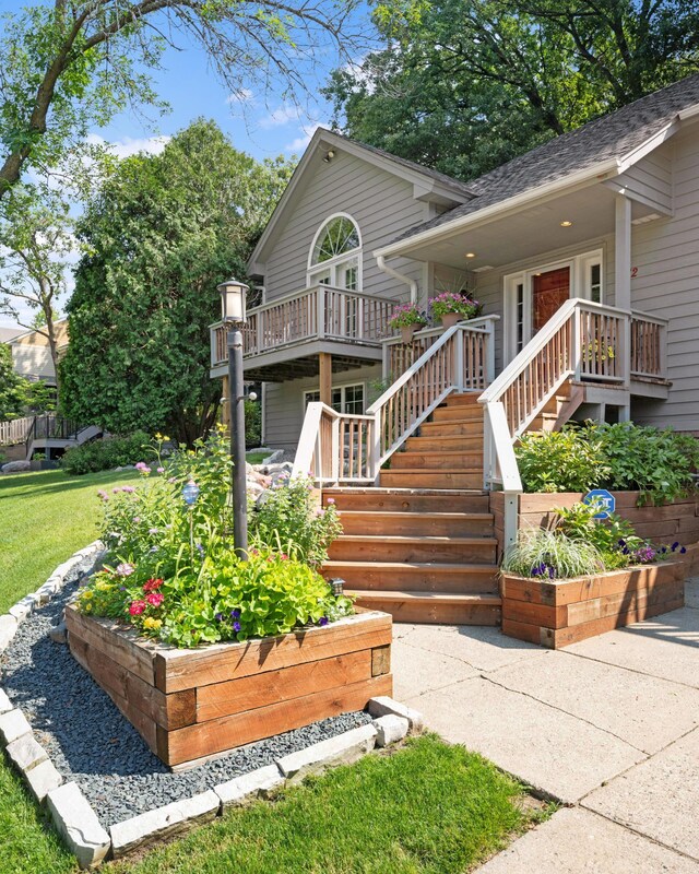 view of front of house with roof with shingles, a deck, a front lawn, and a vegetable garden