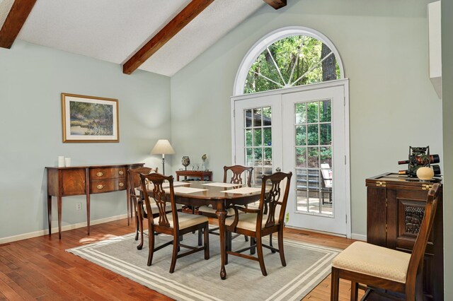 dining space with baseboards, lofted ceiling with beams, and wood finished floors
