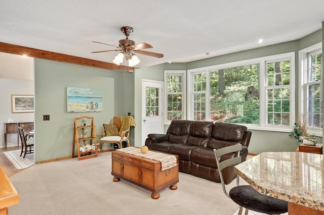 living area with a ceiling fan, baseboards, and light colored carpet