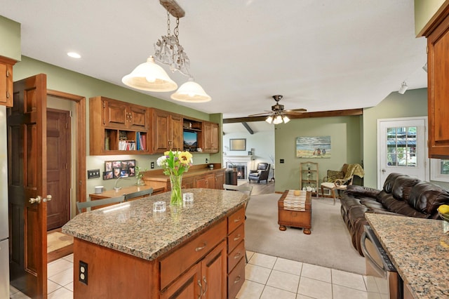 kitchen with light stone countertops, a center island, decorative light fixtures, open floor plan, and light tile patterned floors