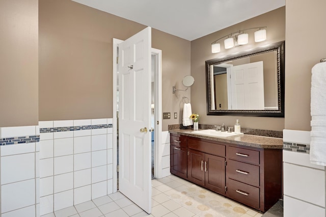 bathroom featuring vanity, tile patterned flooring, wainscoting, and tile walls