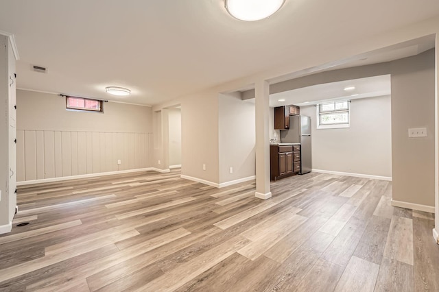 basement with light wood finished floors, visible vents, baseboards, and freestanding refrigerator