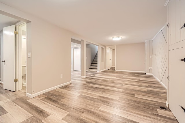 finished basement featuring baseboards, stairway, and light wood finished floors