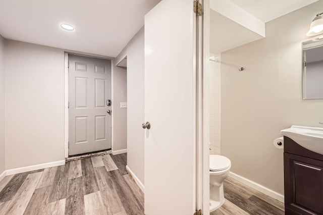 bathroom featuring toilet, baseboards, wood finished floors, and vanity