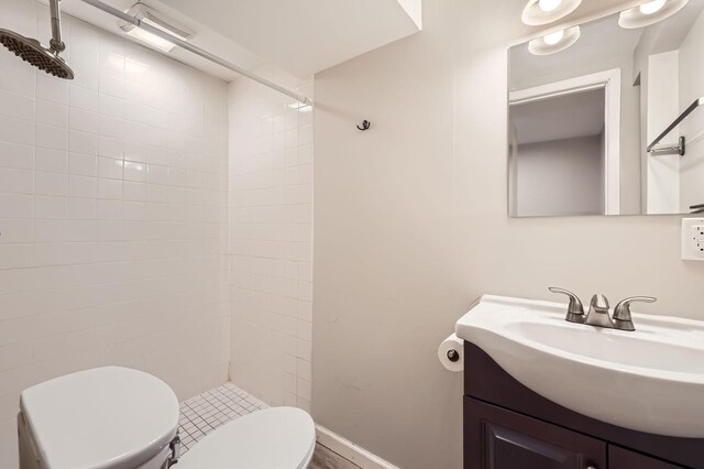 bathroom featuring vanity, toilet, baseboards, and tiled shower