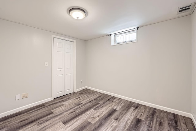 basement with baseboards, dark wood-style floors, and visible vents