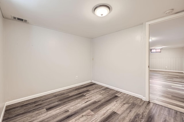empty room with baseboards, visible vents, and wood finished floors