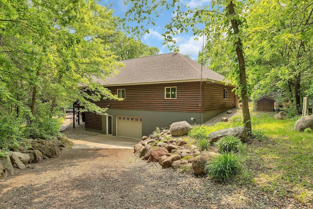 26182 Jericho Rd, Saint Joseph Twp, MN 56301 - view of property exterior with dirt driveway, an attached garage, roof with shingles, and log veneer siding