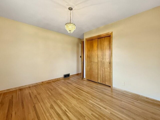 1254 State St, Fairmont, MN 56031 - empty room featuring light wood-type flooring, visible vents, baseboards, and a notable chandelier