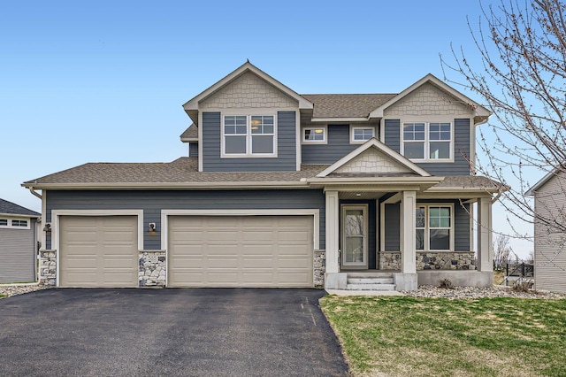 craftsman-style home with a porch, roof with shingles, driveway, and stone siding