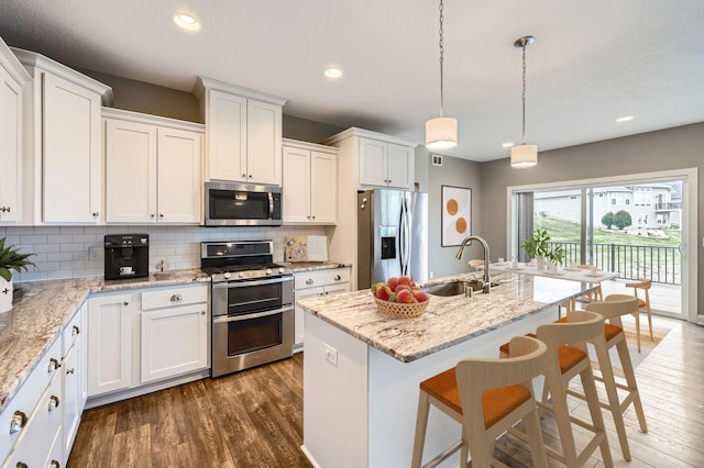 kitchen featuring decorative backsplash, appliances with stainless steel finishes, a sink, white cabinets, and dark wood-style floors