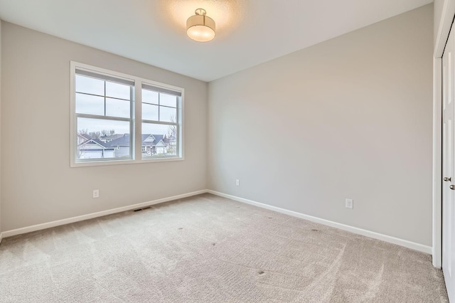 carpeted spare room featuring baseboards and visible vents
