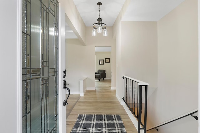 entrance foyer with light wood finished floors, baseboards, and a notable chandelier