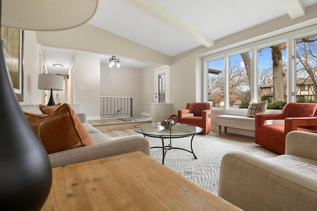 living area featuring baseboards, wood finished floors, beam ceiling, and a healthy amount of sunlight