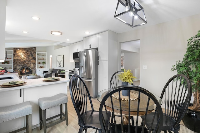 dining area with recessed lighting, light wood-style floors, a stone fireplace, and built in features