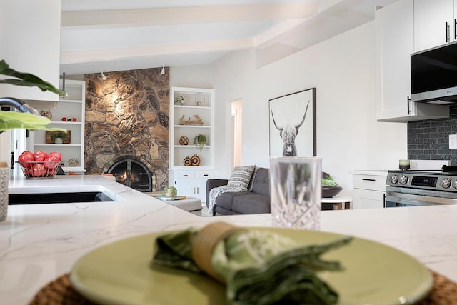 interior space with vaulted ceiling with beams and a fireplace