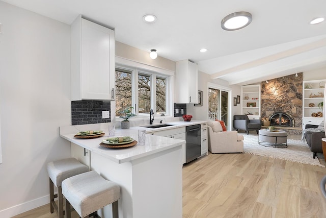 kitchen featuring white cabinets, a sink, open floor plan, a kitchen bar, and black dishwasher