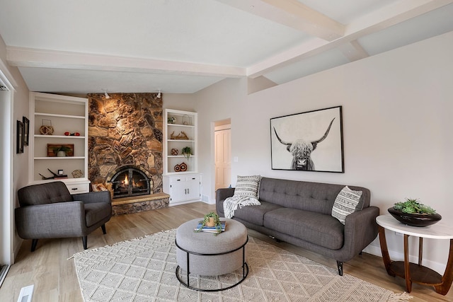 living area featuring light wood finished floors, vaulted ceiling with beams, baseboards, and a fireplace