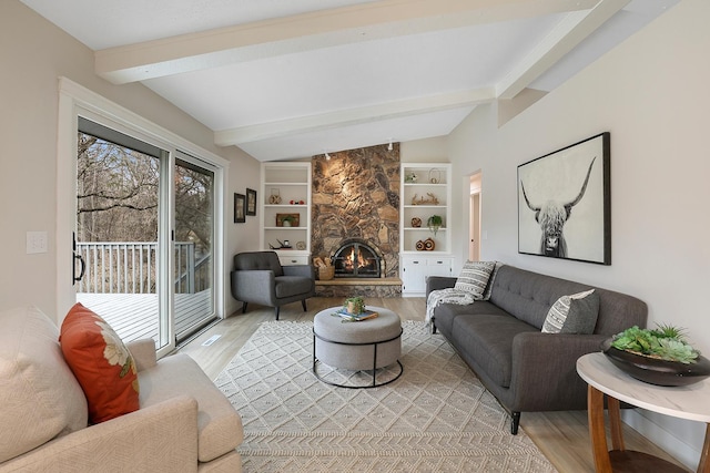 living area with light wood finished floors, built in features, a fireplace, and beamed ceiling