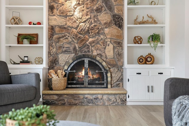living room featuring a stone fireplace and built in shelves