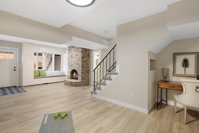 interior space with a fireplace, light wood-type flooring, baseboards, and stairs
