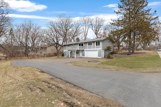 view of front facade with stairway, a chimney, driveway, a front yard, and a garage
