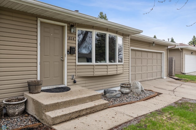 view of exterior entry with a garage and concrete driveway