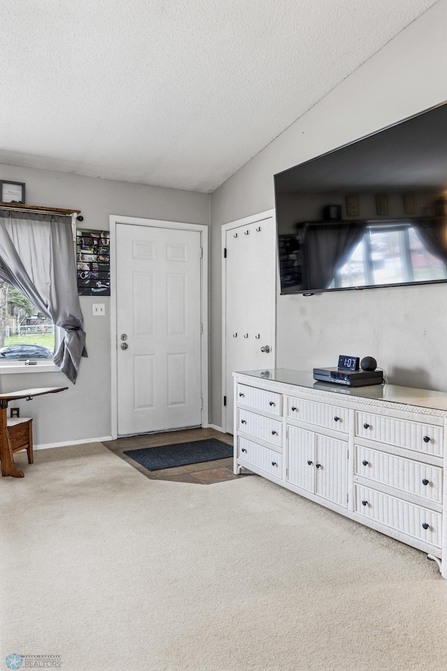 living area featuring light carpet, a textured ceiling, and baseboards