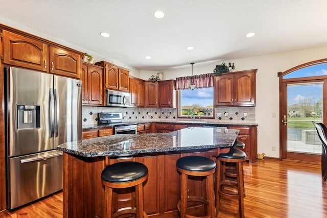 kitchen featuring light wood-type flooring, a sink, a kitchen breakfast bar, and stainless steel appliances