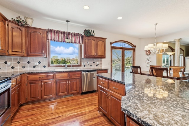 kitchen featuring pendant lighting, a sink, a notable chandelier, stainless steel appliances, and light wood-style flooring