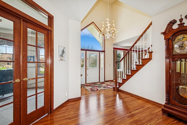 entryway featuring a chandelier, french doors, baseboards, wood finished floors, and stairway