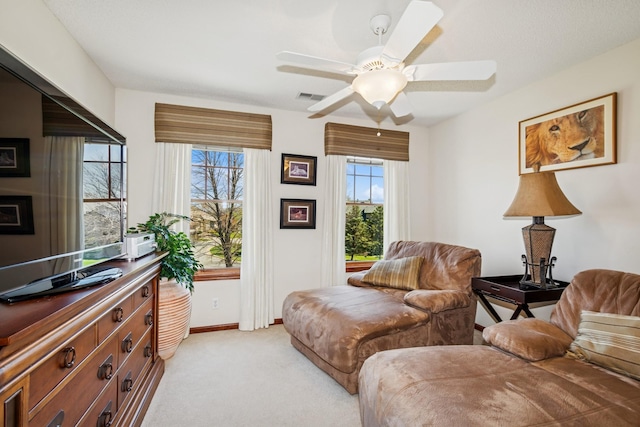 sitting room with baseboards, light carpet, a ceiling fan, and visible vents