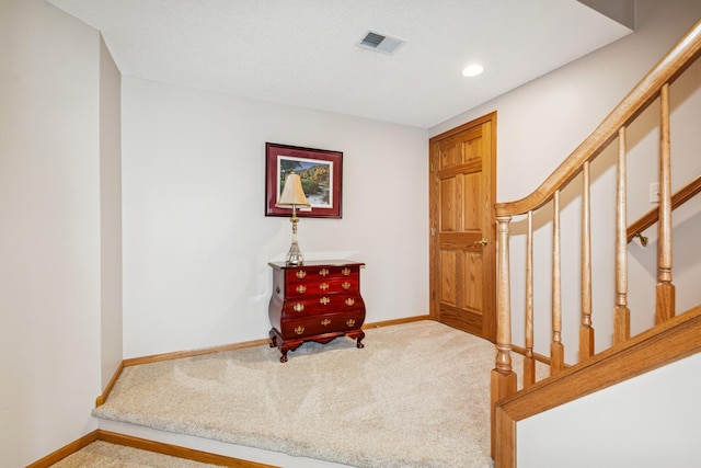 entryway featuring visible vents, carpet, baseboards, and stairway