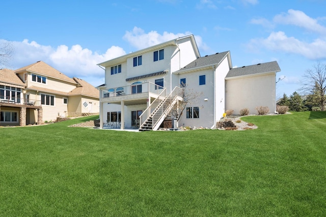rear view of property featuring a lawn, a deck, stucco siding, and stairway