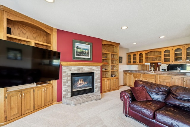 living area featuring recessed lighting, a textured ceiling, a brick fireplace, and light carpet