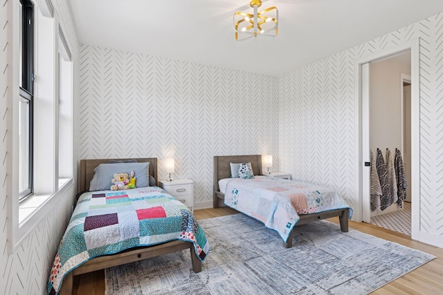 7450 73rd Ct N, Grant, MN 55082 - bedroom featuring wallpapered walls, an accent wall, a chandelier, and light wood-style floors