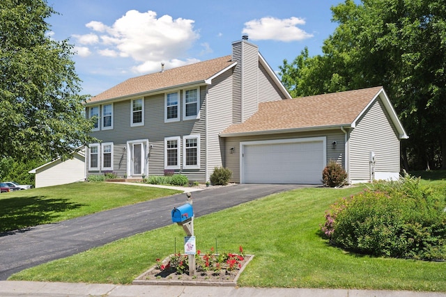 colonial-style house featuring a garage, aphalt driveway, a front yard, roof with shingles, and a chimney