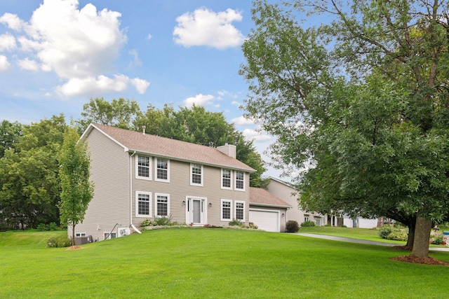 colonial-style house featuring a garage, driveway, a front yard, and a chimney